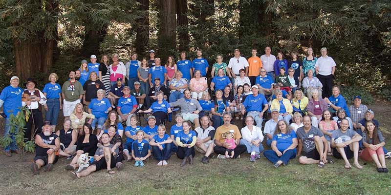 Extended family group photo of the Nielsen family outdoors in front of a forest.